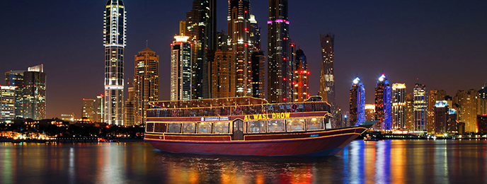 A traditional wooden boat carrying passengers on calm blue waters under a clear sky in Musandam 