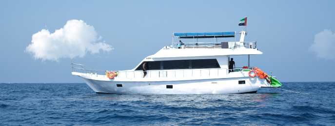 A traditional wooden boat carrying passengers on calm blue waters under a clear sky in Musandam 