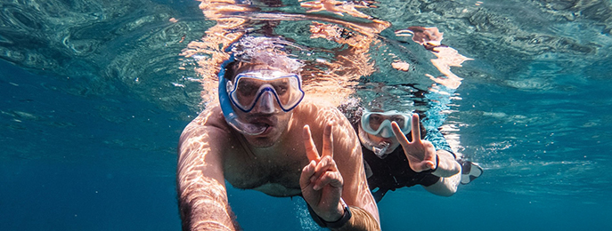 A traditional wooden boat carrying passengers on calm blue waters under a clear sky in Musandam 