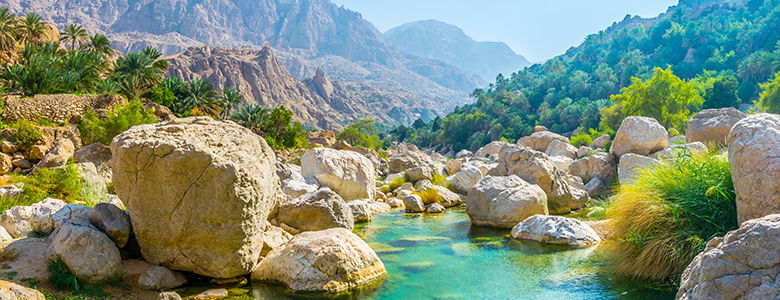 A traditional wooden boat carrying passengers on calm blue waters under a clear sky in Musandam 