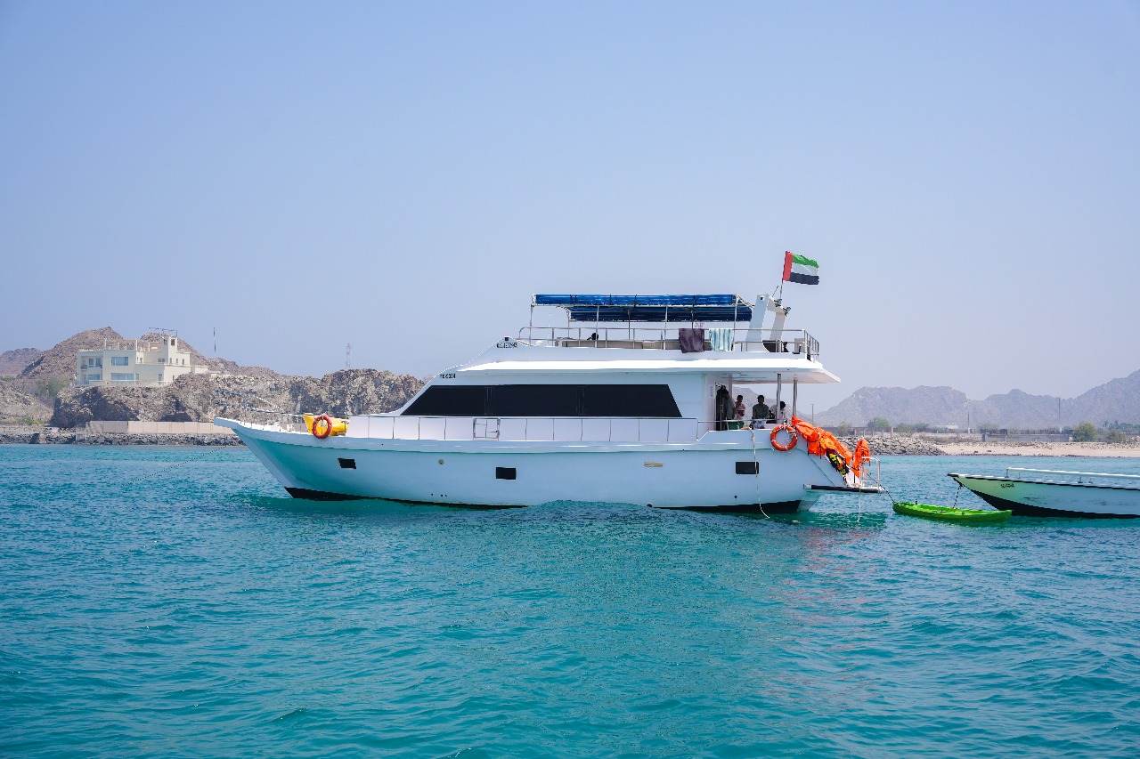 A traditional wooden boat carrying passengers on calm blue waters under a clear sky in Musandam 