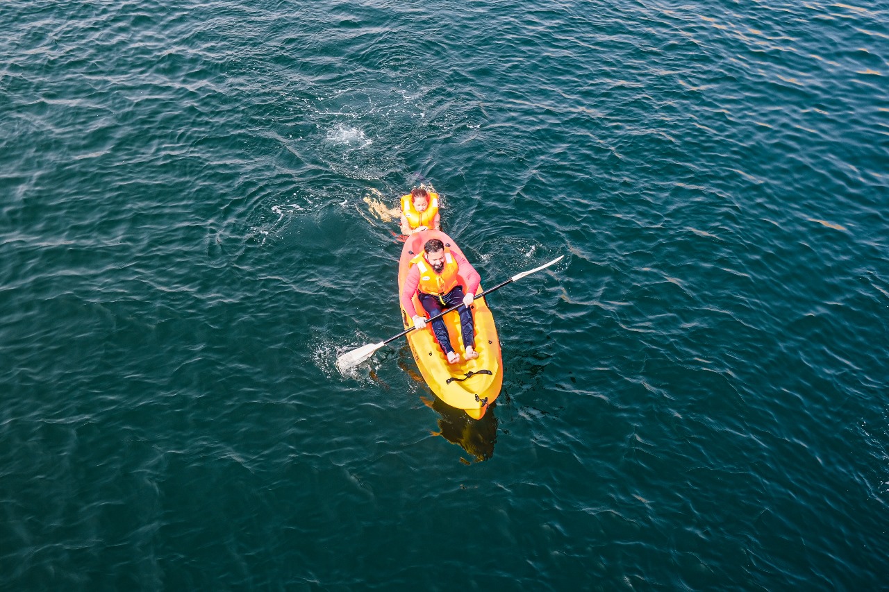 A traditional wooden boat carrying passengers on calm blue waters under a clear sky in Musandam 