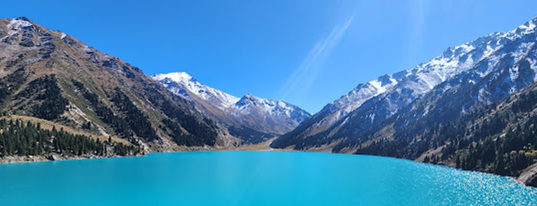 A traditional wooden boat carrying passengers on calm blue waters under a clear sky in Musandam 