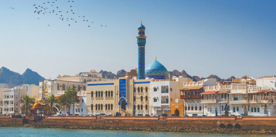 A traditional wooden boat carrying passengers on calm blue waters under a clear sky in Musandam 